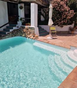 una piscina con sombrilla junto a una casa en Casa Anon, en Jimena de la Frontera