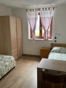 1 Schlafzimmer mit 2 Betten, einem Tisch und einem Fenster in der Unterkunft Villetta sulle dolomiti in Pracorno di Rabbi