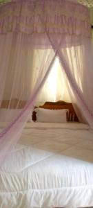 1 dormitorio con cama con dosel y sábanas blancas en Nilenian Holiday Villas, en Jinja
