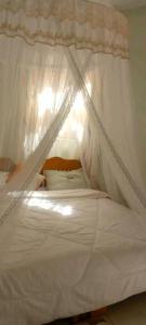un letto bianco a baldacchino in una stanza di Nilenian Holiday Villas a Jinja
