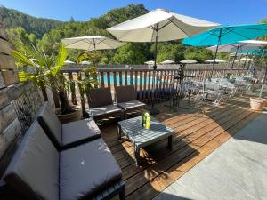 une terrasse en bois avec des chaises, des tables et des parasols dans l'établissement Camping du Bourg, à Digne-Les-Bains