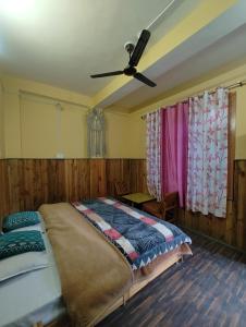 a bedroom with a bed and a ceiling fan at Corridor Homestay in Sainj