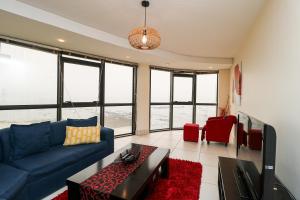 - un salon avec un canapé bleu et des fauteuils rouges dans l'établissement Ocean View 304 Luxury Self Catering Apartment Strand Western Cape South Africa, au Cap