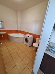 a bathroom with a tub and a washing machine in it at Hotelak Martinov in Ostrava