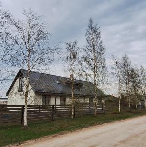 een wit huis met een hek en bomen bij Jūras sāga in Pāvilosta
