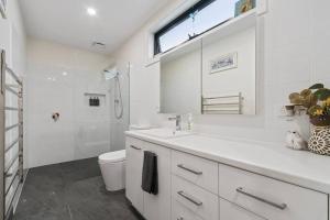 a white bathroom with a sink and a toilet at Joan's Beach Cottage in Mount Martha