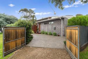 a house with two wooden gates in front of a driveway at Joan's Beach Cottage in Mount Martha
