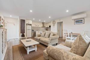 a living room with two couches and a kitchen at Joan's Beach Cottage in Mount Martha