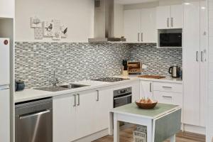 a kitchen with white cabinets and a bowl of fruit on a table at Joan's Beach Cottage in Mount Martha +5 photos