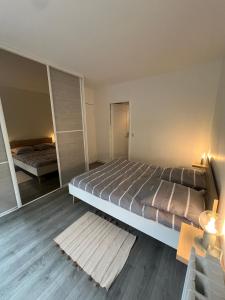 een slaapkamer met een groot bed en een spiegel bij Oasis de Verdure avec Balcons - Proche Versailles in Viroflay