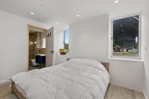 a white bedroom with a bed and a window at Luxury Stargazers Barn; Close to Coast, Town and Trails in Pembrokeshire