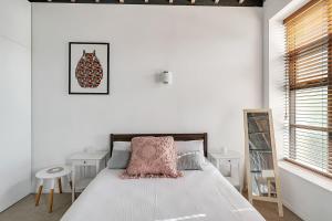 a white bedroom with a bed with a pink pillow at STYLISH APARTMENT IN CHIPPENDALE //PRIVATE PARKING in Sydney