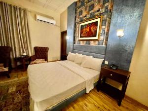 a hotel room with a bed and a chair at Shelton Hotel Mardan in Mardan