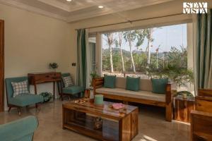 sala de estar con sofá y ventana grande en StayVista's Silver Slopes - Mountain-View Villa with Outdoor Pool, Expansive Lawn featuring a Gazebo & Terrace, en Chandīgarh