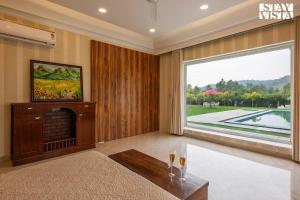 een woonkamer met een open haard en een groot raam bij StayVista's Silver Slopes - Mountain-View Villa with Outdoor Pool, Expansive Lawn featuring a Gazebo & Terrace in Chandīgarh