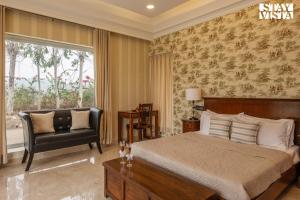 - une chambre avec un lit, une chaise et une fenêtre dans l'établissement StayVista's Silver Slopes - Mountain-View Villa with Outdoor Pool, Expansive Lawn featuring a Gazebo & Terrace, à Chandigarh