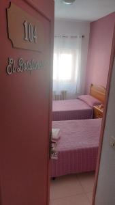 Habitación con 2 camas, paredes de color rosa y puerta. en Casadidoru en Mansilla de las Mulas