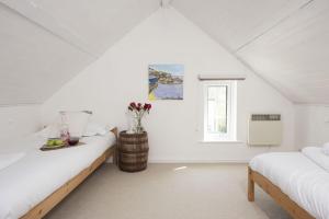 a white attic bedroom with two beds and a window at Rutherglen in Porthallow