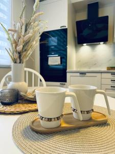 dos tazas de café sentadas en una bandeja de madera en una mesa en Apartment Tullikatu, en Kristinestad