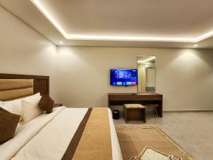 a bedroom with a bed and a desk and a tv at Olaya Residence in Riyadh