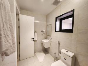 a white bathroom with a toilet and a sink at Olaya Residence in Riyadh