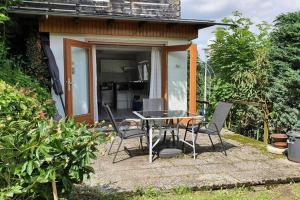 a patio with a table and chairs in front of a house at Modern apartment near Willingen with private terrace and use of garden in Willingen