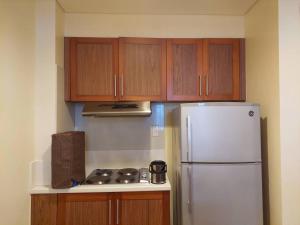 a kitchen with a white refrigerator and wooden cabinets at 2BR Penthouse in Anvaya Cove in Morong