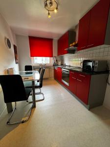 cocina con armarios rojos, mesa y sillas en Apartments Morneweg, en Kronberg im Taunus