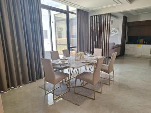 une salle à manger avec une table et des chaises en verre dans l'établissement luxurious villa, à Al Budayyiâ€˜