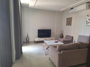 uma sala de estar com um sofá e uma televisão em luxurious villa em Al Budayyiâ€˜