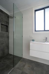 a bathroom with a glass shower and a sink at Rosa - Beach Studio Getaway in Vincentia