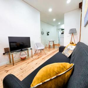 sala de estar con sofá y TV de pantalla plana en Casas da Ferraria by 4U Alojamento - Tonho da Chica & Avô Marchão, en Abrantes