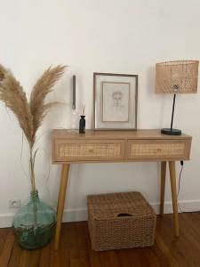 einem Holztisch mit einer Vase und einem Bild darauf in der Unterkunft Profitez de la golden hour depuis Levallois ! in Levallois-Perret