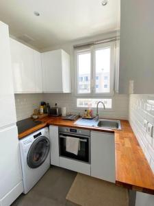 eine Küche mit einer Waschmaschine und einem Waschbecken in der Unterkunft Profitez de la golden hour depuis Levallois ! in Levallois-Perret