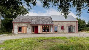 una piccola casa in mattoni con una porta rossa di Luxury Stargazers Barn; Close to Coast, Town and Trails a Pembrokeshire
