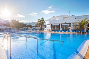 una gran piscina con sillas azules y un edificio en THB Lanzarote Beach, en Costa Teguise