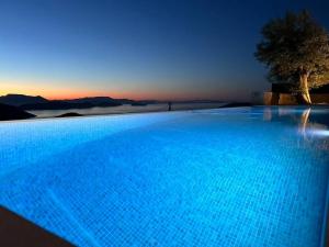 a blue swimming pool with a sunset in the background at Go-Blue Star, Villa Sea in Sivota