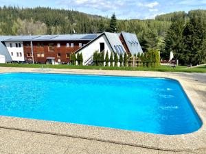 a large blue swimming pool in front of a house at Horský hotel Brans in Malá Morávka