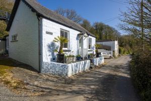 a white house with potted plants on the side of it at Rutherglen in Porthallow