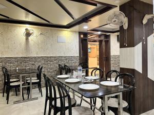 uma sala de jantar com mesas e cadeiras e uma parede de tijolos em Hotel Binapani em Tarapith
