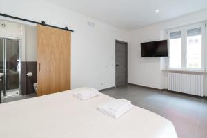 Schlafzimmer mit einem weißen Bett und einem Flachbild-TV in der Unterkunft Camere Cavour in Macerata