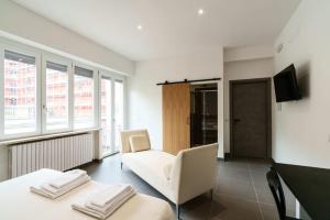 a living room with two white chairs and a tv at Camere Cavour in Macerata