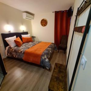 una camera da letto con un letto e un piumone arancione di Hôtel L'Etoile Aéroport - A61 a Carcassonne
