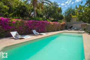 una piscina con due sedie e fiori viola di Villa Ana Clara by Abahana Villas ad Altea