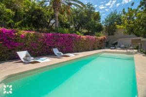 a swimming pool with two chairs and purple flowers at Villa Ana Clara by Abahana Villas in Altea la Vieja