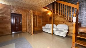 ein Wohnzimmer mit 2 weißen Stühlen und einer Treppe in der Unterkunft HanHome in Talghar