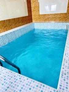 a large swimming pool with blue water in a room at HanHome in Talghar