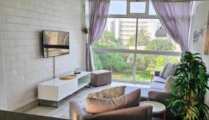 a living room with furniture and a large window at La Ballito 305 in Ballito