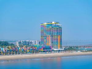 a tall building on a beach next to the ocean at Flamingo Ibiza Hải Tiến in Nam Khê