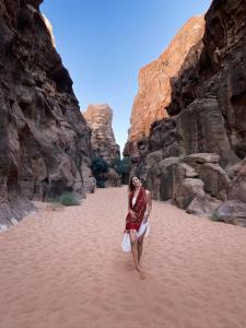 a woman walking through the sand in a canyon at Wadi Rum Bedouin Heart Camp in Wadi Rum